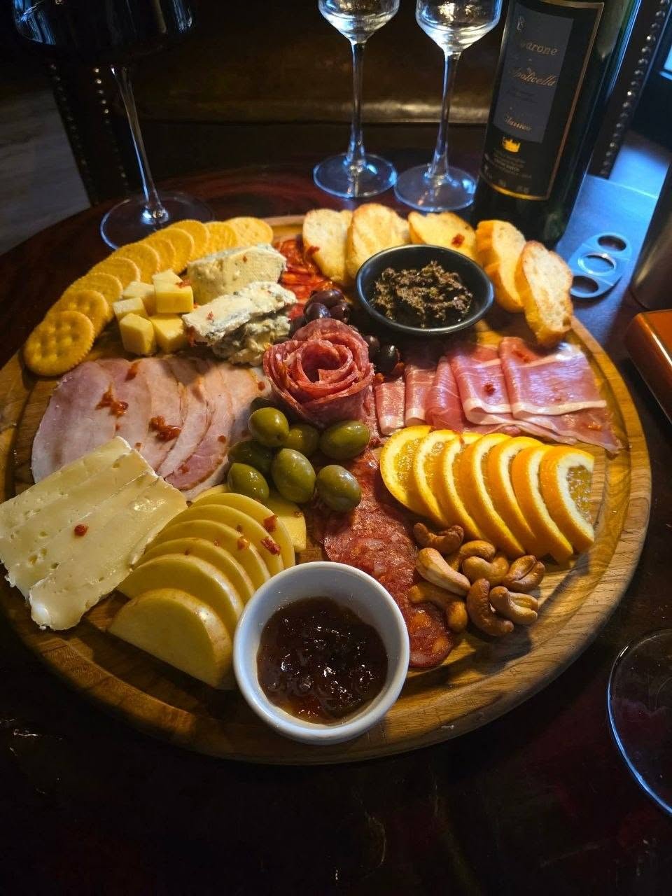 charcuterie board with cheeses, cured meats, olives, wine