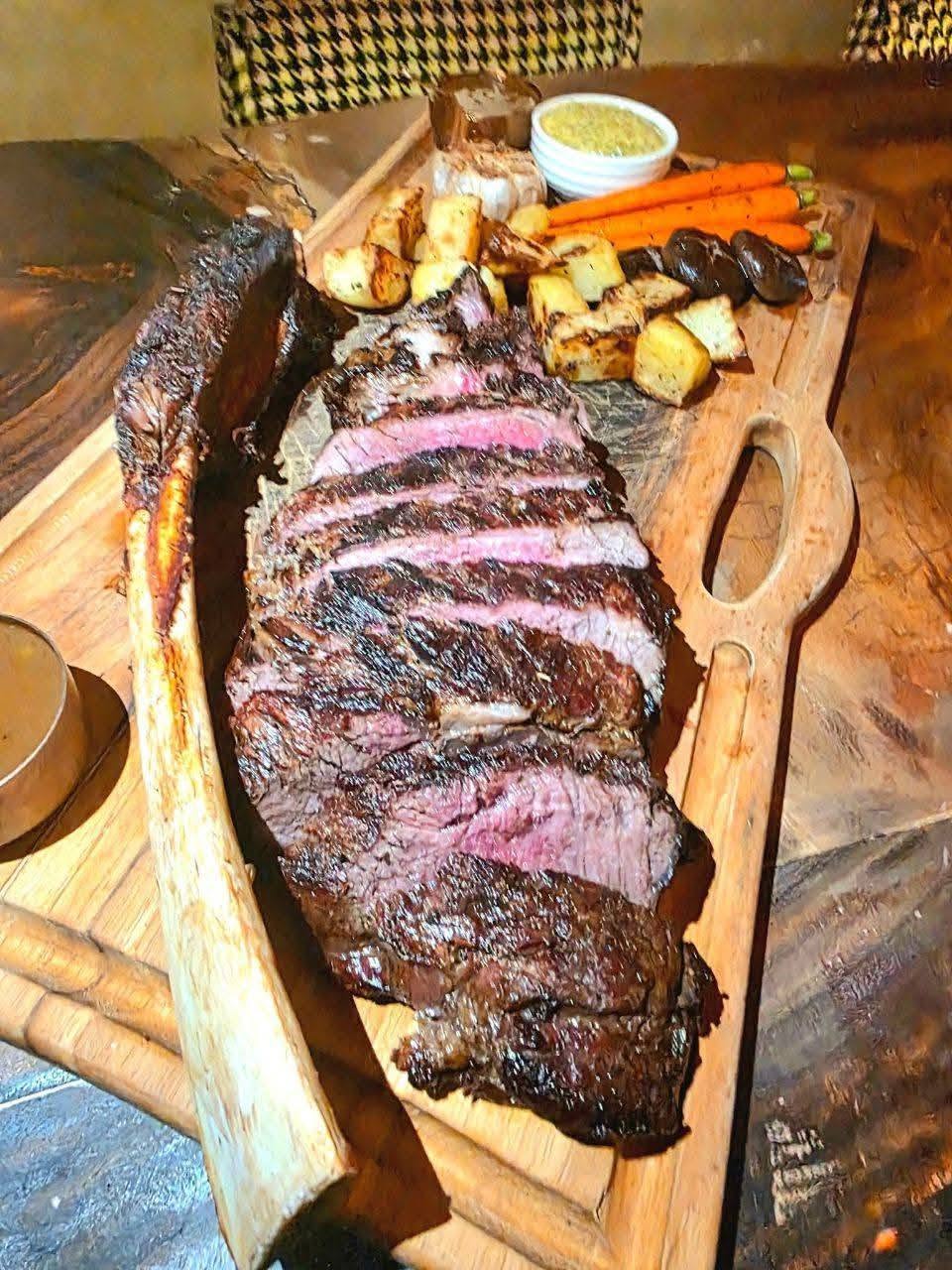 grilled steak on wooden platter with roasted vegetables