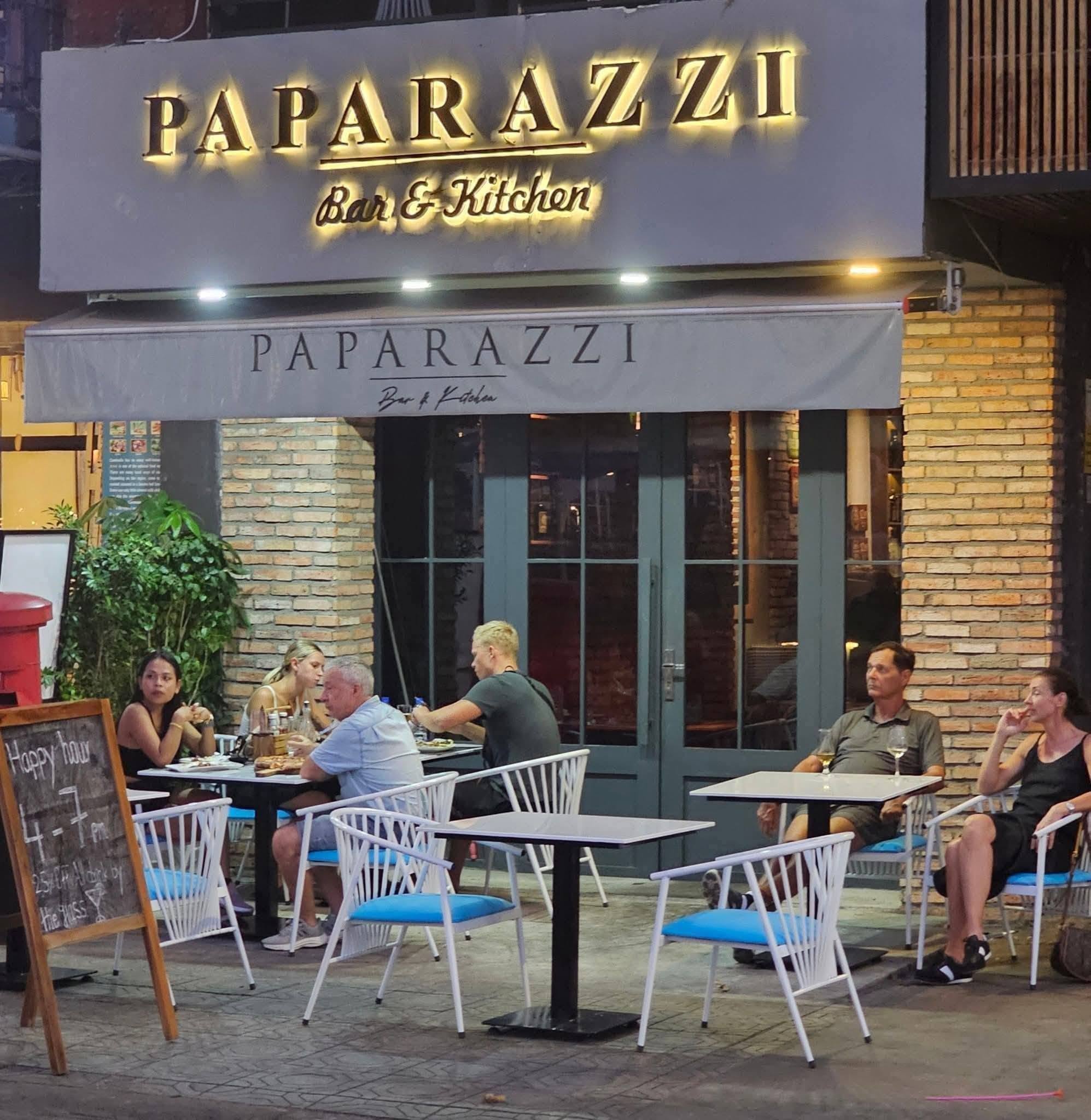 Paparazzi storefront with outdoor seating and Happy Hour chalkboard