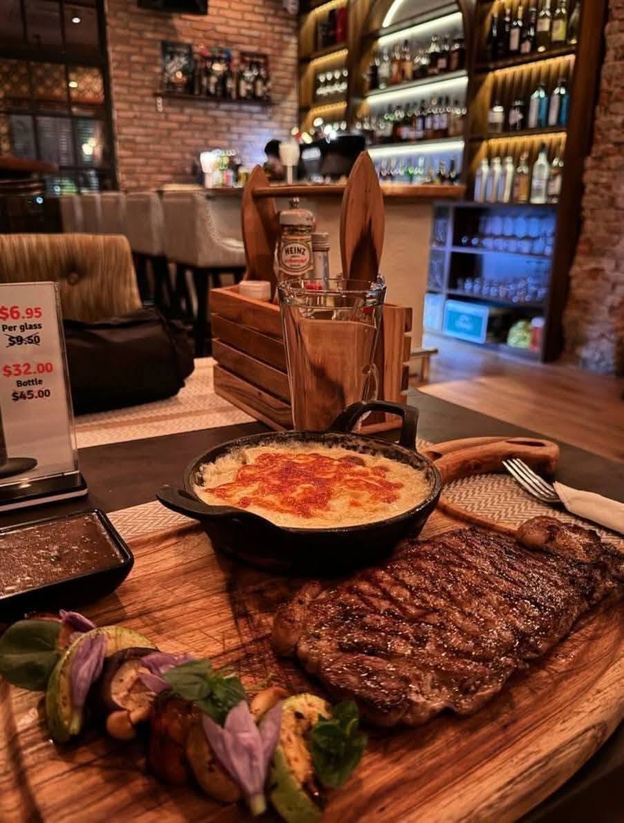 grilled steak with vegetables and gratin, bar in background